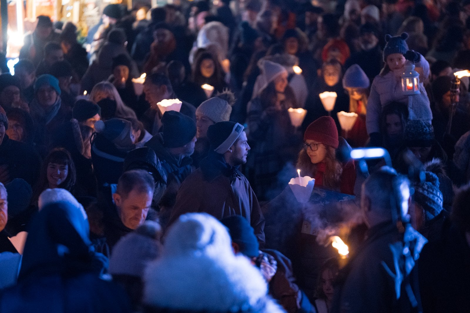 La foule tient des bougies allumées sur la place