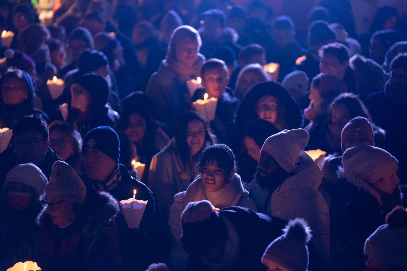 Des visages dans la foule, bougies à la main, dans la lumière bleue de la nuit